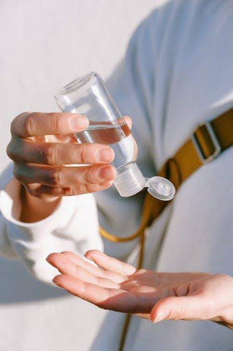 Person using hand sanitiser, wearing a stoma travel bag